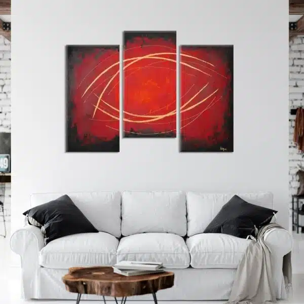 tableau triptyque abstrait rouge et noir dans un salon moderne au dessus d'un canapé blanc et noir.