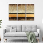 tableau triptyque marron or sur mur blanc au dessus d'un canapé gris avec une couverture verte sur le dessus.