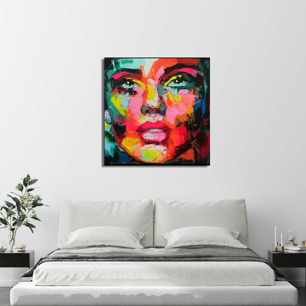 Toile moderne au couteau visage d'une femme Tableau d'un visage femme multicolore style pop, accroché au-dessus d'un lit, 2 tables de chevet noirs avec une plante à gauche et des bougeoirs à droite