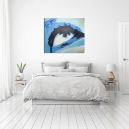 Tableau d'un œil en gros plan aux couleurs bleus, accroché au-dessus d'un lit avec des tables de chevet avec une plante verte et un réveil à gauche et une lampe à droite