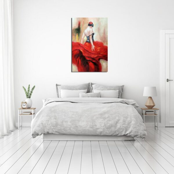 Tableau d'une danseuse de flamenco de dos avec une jupe à volant rouge et un bustier noir, accroché au-dessus d'un lit, 2 tables de chevet avec à gauche une plante et un réveil et à droite une lampe