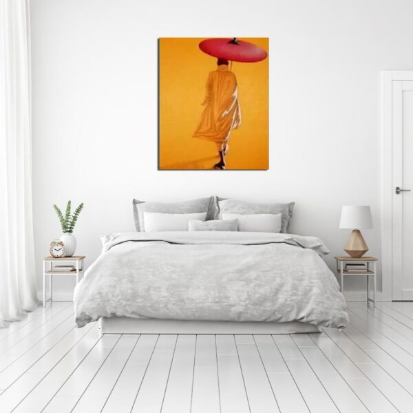 Tableau tons orange chaud avec un moine et son ombrelle marchant de dos, au-dessus d'un lit avec 2 tables de chevet en métal et plateau bois sur la gauche une plante et un réveil et sur la droite une lampe