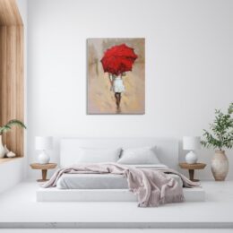 Tableau d'une femme à l'imperméable blanc et un grand parapluie rouge cachant tout le haut du corps, accroché au-dessus d'un lit avec un plaid rose pâle tombant du bout du lit, 2 tables de chevet en bois avec chacune une lampe blanche, un vase en terre cuite avec une plante verte sur la droite