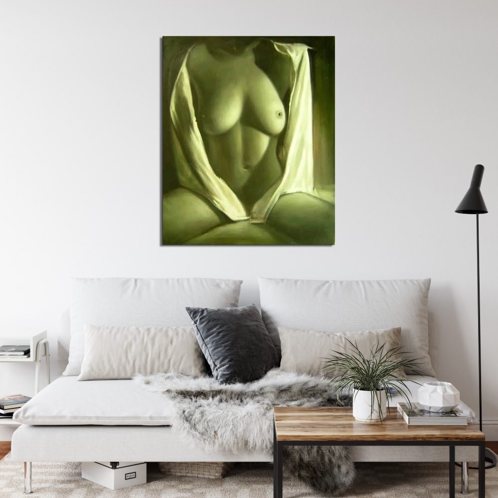 Tableau femme nue chemise blanche Tableau d'une femme assise, jambes écartées, habillé d'une chemise ouverte, accroché au-dessus d'un canapé avec 2 gros coussins blanc et un petit coussin noir, une table basse avec structure métal noir et un plateau en bois devant et une lampe sur pied dans le coin droit