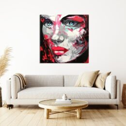 Tableau style pop art d'un visage d'une femme, accrcohé au dessus d'un canapé beige avec des coussins marron beige à droite et une table basse en bois et paille