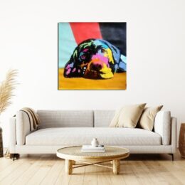 Tableau d'un petit chiot sur un style pop art , accroché au-dessus d'un canapé beige avec des coussins beige, une table en rotin en bous