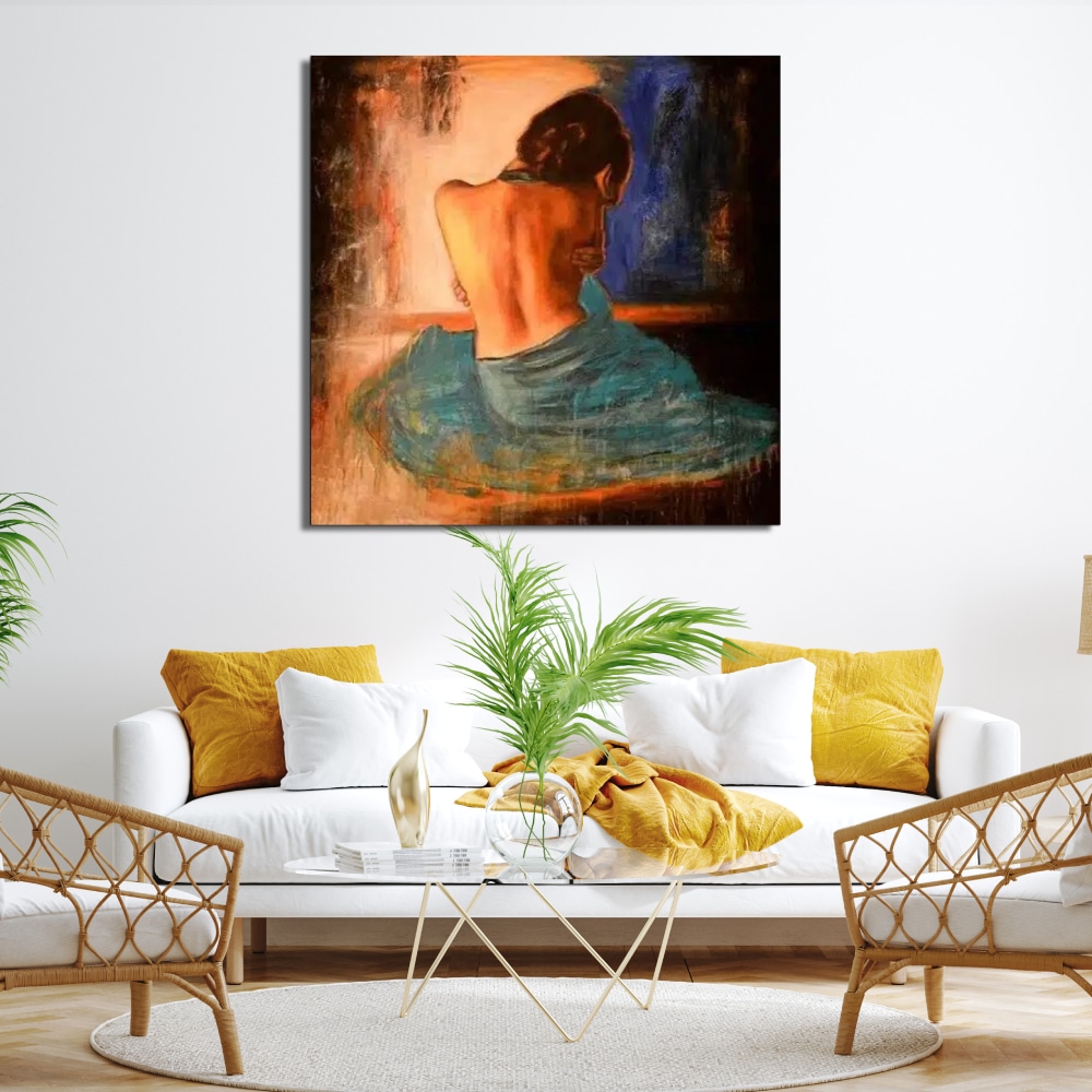 Peinture femme nue vue de dos avec un voile azur Tableau d'une femme assise de côté avec un drap turquoise sur le bas de son corps et le haut nue dans des tons orangé, noir accrcohé au-dessus d'un canapé avec des coussins jaune, une table en verre avec une plante et 2 fauteuils en rotin