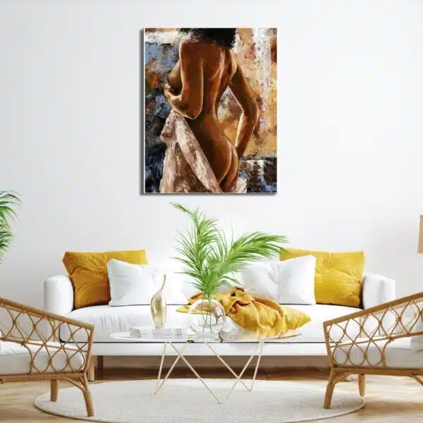 Tableau femme nue métissé avec un drap beige dans la main gauche, au-dessus d'un canapé blanc et jaune moutarde, une table en verre avec une plante dessus et 2 fauteuils en rotin avec coussin blanc