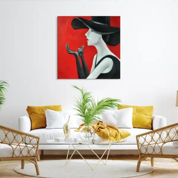 Tableau d'une femme avec un chapeau de profil faisant semblant de se mettre du rouge à lèvre, accroché au-dessus d'un canapé blanc et jaune, une table basse en verre avec une plante verte, 2 fauteuils en rotin