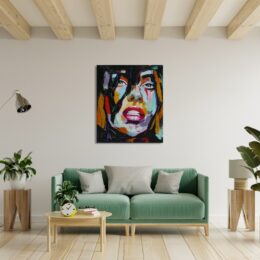Tableau d'un visage d'une femme style pop art, accroché au-dessus d'un canapé vert avec de chaque côté des plantes vertes dans des vases blanc sur des tabouret en bois d'appoint, une table basse en bois devant le canapé