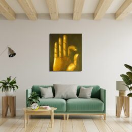 Tableau d'une main de bouddha en couleur or avec l'index et le pouce qui se touchent sur un fond noir, accroché au-dessus d'un canapé vert, 2 tabourets d'appoint en bois avec 2 plantes vertes, une table basse en bois