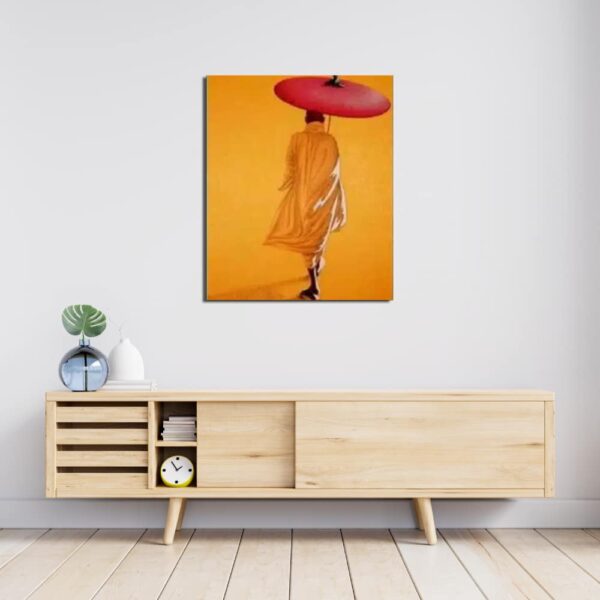 Tableau tons orange chaud avec un moine et son ombrelle marchant de dos , accroché au-dessus d'un meuble en bois avec portes coulissantes et un vase dessus bleu transparent avec une plante