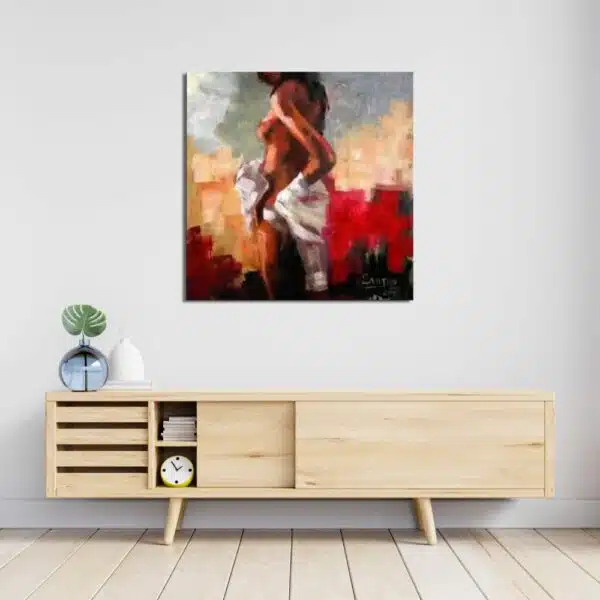 Tableau d'une femme nue de dos, buste tourné avec un drap blanc sur les hanches, dans un fond de couleurs rouge, beige, gris.Accroché au-dessus d'un meuble en bois clair avec des portes coulissantes et un vase transparent bleu avec une plante sur la gauche