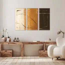 tableau triptyque dégradé marron sur un mur blanc au dessus d'un bureau en bois et d'un fauteuil moderne blanc.