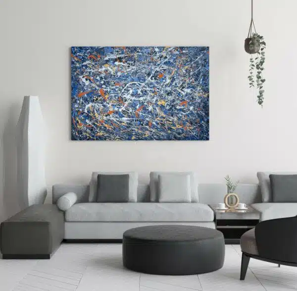 Tableau bleu Jackson Pollock abstraite accroché sur un mur avec un canapé et une table basse dans une maison