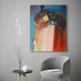 Peinture abstraite bleue rouille, accrochée sur un mur au-dessus d'un canapé et une table dans une salon.