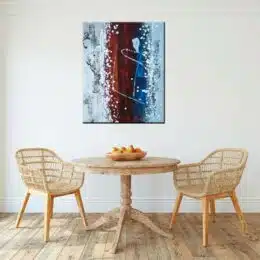 Peinture abstraite bordeaux grise, bleu. Bonne qualité, très original, accrochée sur un mur au-dessus d'une table et des chaises dans une maison.