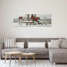 Tableau panoramique gris rouge argent abstrait accroché sur un mur avec un canapé et un table basse dans une maison