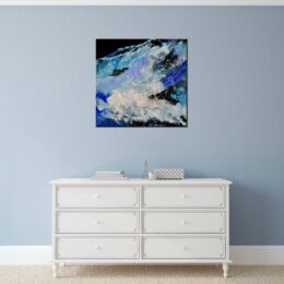 Tableau carré bleu noir abstrait, accrochée sur un mur au-dessus d'une table blanche dans une maison.