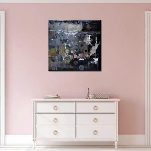 Tableau abstrait gris noir, bonne qualité, très original, accrochée sur un mur rose au-dessus d'une table blanc dans une maison.
