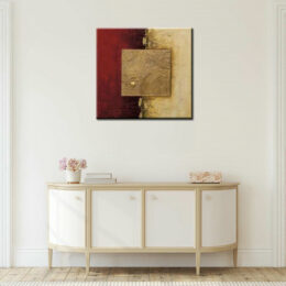 Tableau abstrait carré doré bordeaux, bonne qualité, très original, accrochée sur un mur au-dessus d'une table dans une maison.
