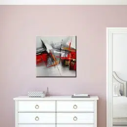Tableau gris rouge abstrait carré reliefs or. Bonne qualité, très original, accrochée sur un mur de couleur rose au-dessus d'une table blanche dans une maison.