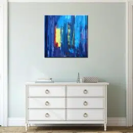 Peinture abstraite carré jaune bleu, bonne qualité, très original accrochée sur un mur au-dessus d'une table blanche dans une maison