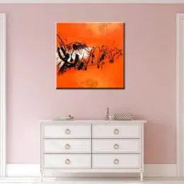 Peinture abstraite carré orange. Bonne qualité, très original, accrochée sur un mur au-dessus d'une table blanche dans une maison.
