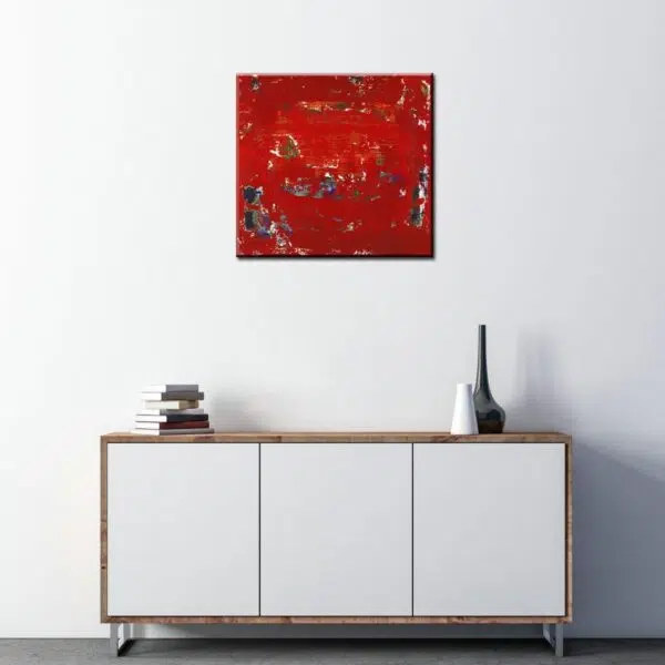 Tableau abstrait rouge noir blanc carré, bonne qualité, très original accrochée sur un mur au-dessus d'une table dans une maison.