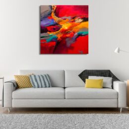 PEINTURE ABSTRAITE ROUGE CARRÉ MULTICOLORE ACCROCHE SUR UN MUR AU-DESSUS D'UN CANAPÉ DANS UNE MAISON