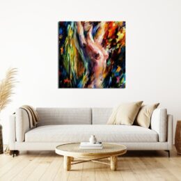 Tableau coloré multicolore peint au couteau représentant une femme bras levés avec les mains dans les cheveux au-dessus d'un canapé beige avec des petits coussins beige nacré sur la droite et une table basse en marron claire sur un parquet en bois