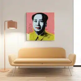 Tableau de Mao avec une chemise jaune sur un fond rose, accrcohé au-dessus d'un canapé jaune avec une lampe sur pied à gauche