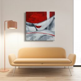 Tableau d'une femme aux lèvres rouge, le visage posé sur ses avant-bras portant un chapeau rouge cachant ses yeux, accroché au-dessus d'un canapé jaune avec une lampe sur pied sur la gauche