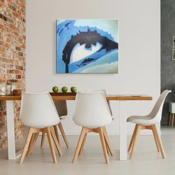 Tableau d'un œil en gros plan aux couleurs bleus, accroché face à une table en bois contre un mur en briquettes, avec 5 chaises blanches avec les pieds en bois