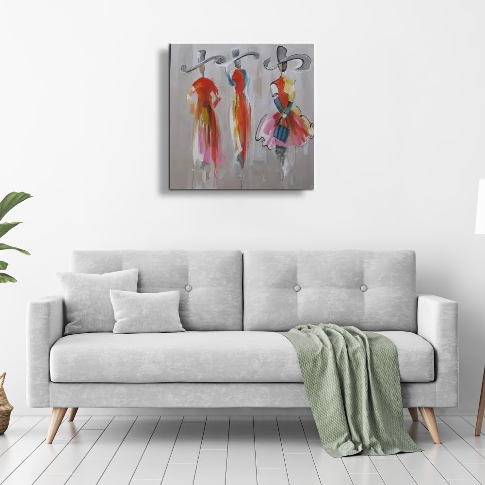 Peinture moderne les filles au chapeau Tableau au fond gris de 3 femmes avec des chapeaux, accrcohé au-dessus d'un canapé avec des coussins à gauche et un plaid vert à gauche