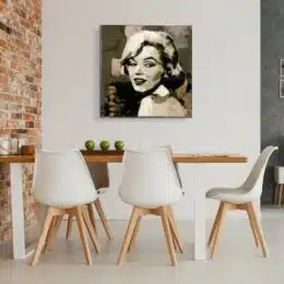 Tableau de Marilyn Monroe dans un style sépia, accroché face à une table en bois marron et 5 chaises blanches avec les pieds en bois