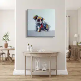 Tableau style pop art d'un petit chien aux couleurs gris, bleu, jaune, accroché au-dessus d'une console en demi-cercle en bois avec des vases sur la gauche et des lampes en dessous