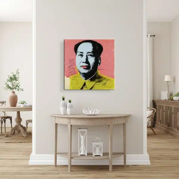 Tableau de Mao avec une chemise jaune sur un fond rose, accroché au-dessus d'une console en demi-cercle en bois patiné, des vases avec des fleurs sur la gauche et des lampes en dessous