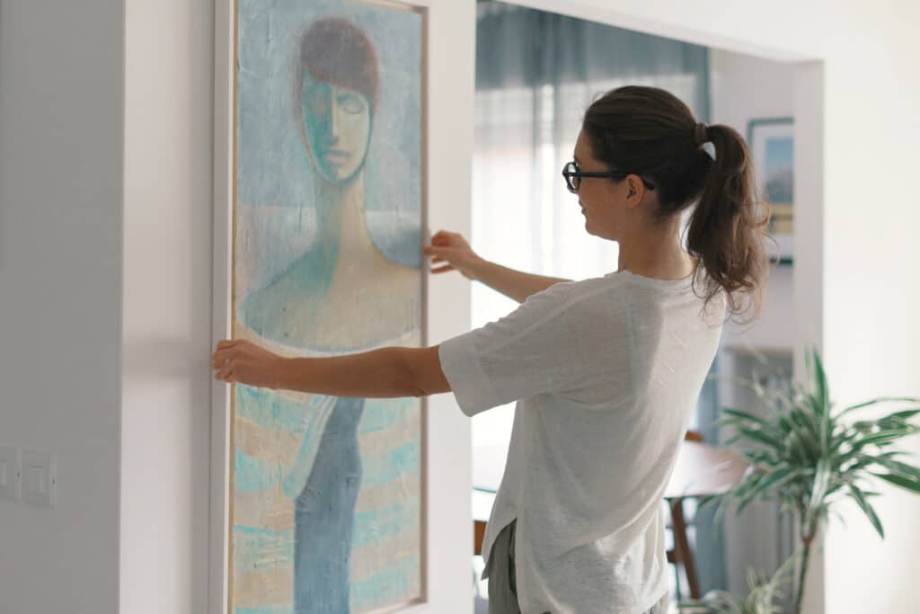 Femme qui accroche une peinture à l'huile sur son mur