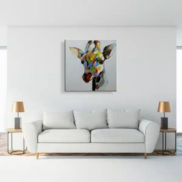 Tableau style pop art d'une girafe multicolore, accroché au-dessus d'un canapé blanc, 2 tables d'appoint avec 2 lampes