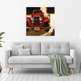 Tableau d'une voiture de collection rouge des années 40, accroché au-dessus d'un canapé gris avec un plaid vert