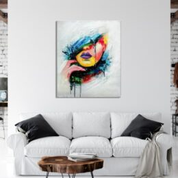 Tableau d'un visage style pop art, accrcohé au-dessus d'un canapé blanc avec 2 coussins noirs, une table basse en bois