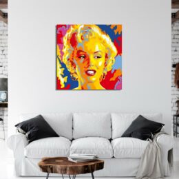 Tableau de Marilyn Monroe en style pop art , accroché au-dessus d'un canapé blanc avec 2 coussins noir et une table basse en bois marron