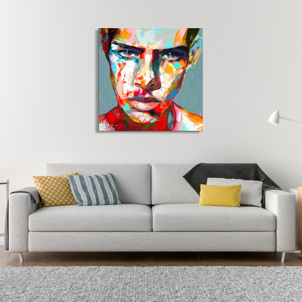 Tableau peinture moderne au couteau visage homme Tableau style popart d'un visage d'une femme aux couleurs vivent, accroché au-dessus d'un canapé gris avec plusieurs coussins multicolore